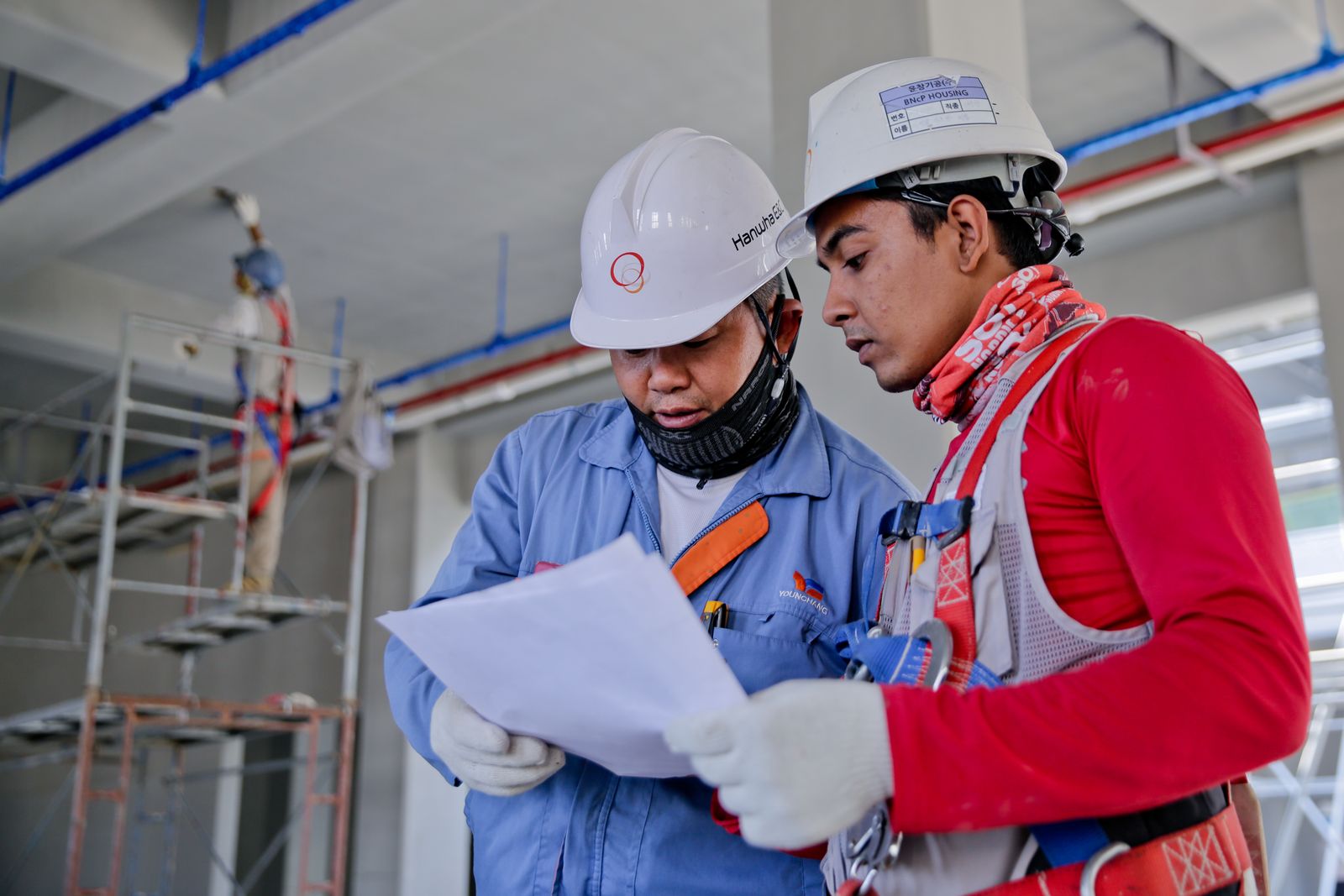 Two builders in hard hats reviewing plans on site